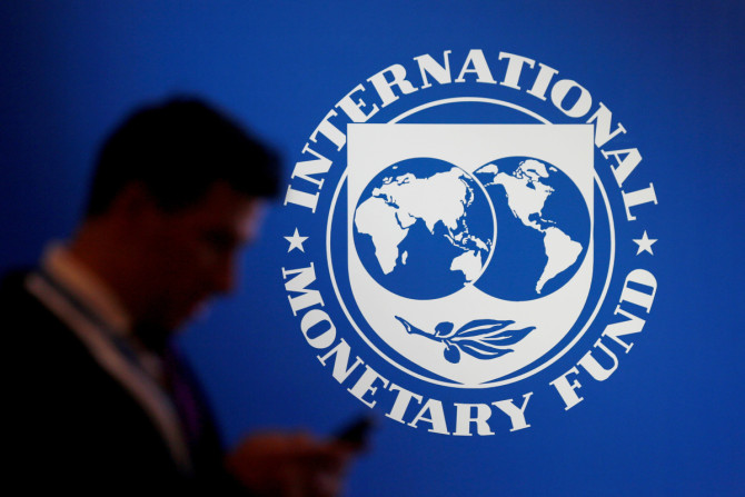 Un participante se encuentra cerca de un logotipo del FMI en el Fondo Monetario Internacional - Reunión Anual del Banco Mundial 2018 en Nusa Dua