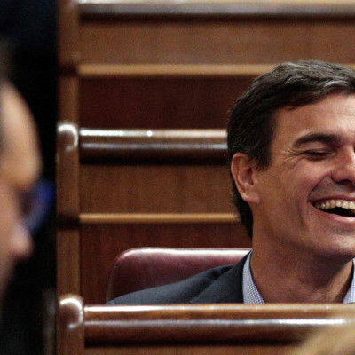 El exlíder del PSOE Sánchez se ríe frente al portavoz parlamentario socialista Hernando durante el debate de investidura en el Parlamento de Madrid.