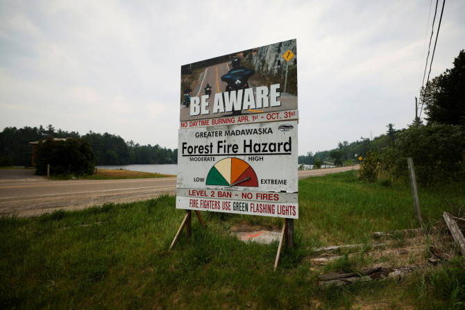 Una señal de peligro de incendio se encuentra al lado de una carretera cerca de un incendio forestal que ha estado ardiendo desde el domingo en la orilla del lago Centennial en el municipio de Greater Madawaska