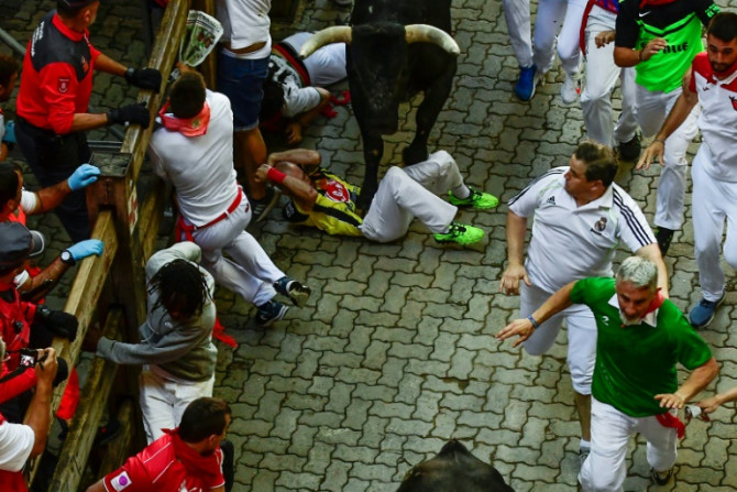 Un hombre es pisoteado por un toro durante la octava y última corrida de toros de las famosas fiestas de San Fermín en España.