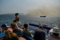 El humo de los incendios formaba parte del paisaje para los turistas en un ferry a la isla griega de Corfú.