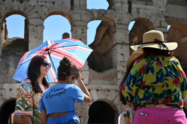 Turistas protegidos del sol con sombrillas en el Coliseo de Roma